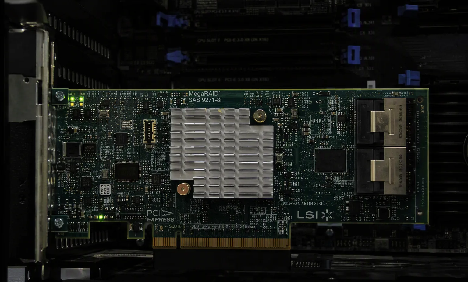 MegaRAID controller installed into a server PCIe slot with indicator LEDs lit, dark chassis interior.