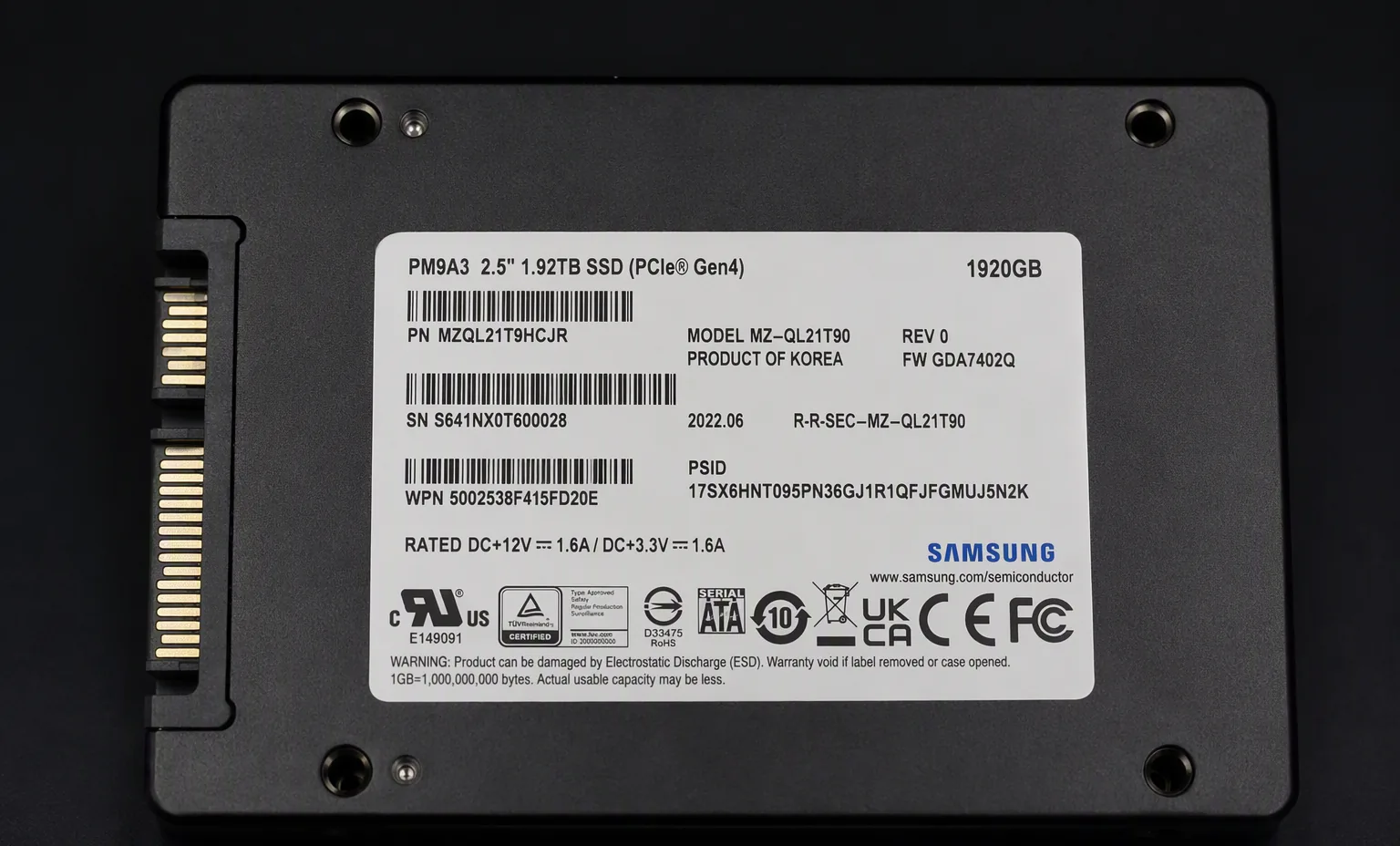 Samsung PM9A3 1.92TB enterprise U.2 NVMe SSD, label top view, dark studio macro shot.