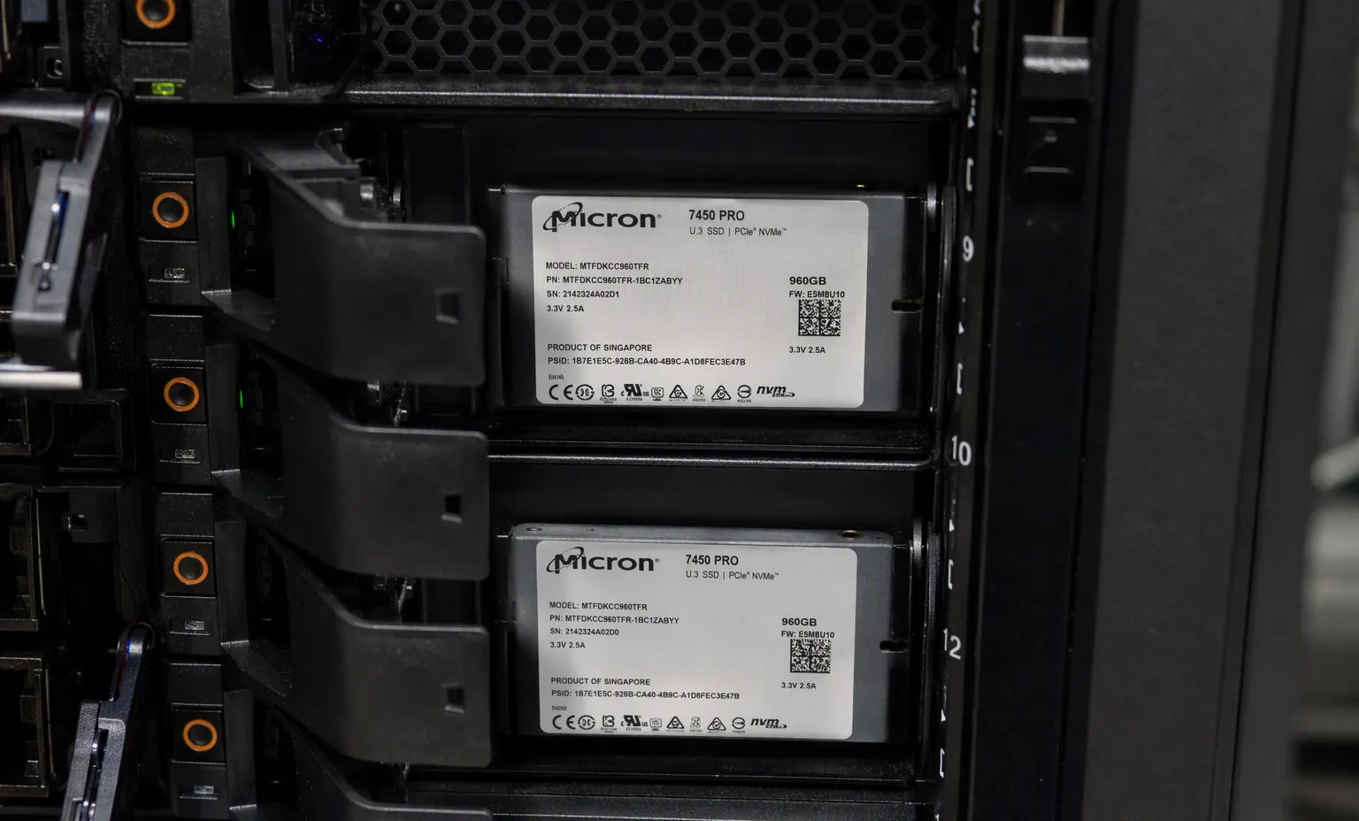 2.5 inch enterprise SSDs populated in a server hot-swap front bay cage, close-up, dark rack environment.
